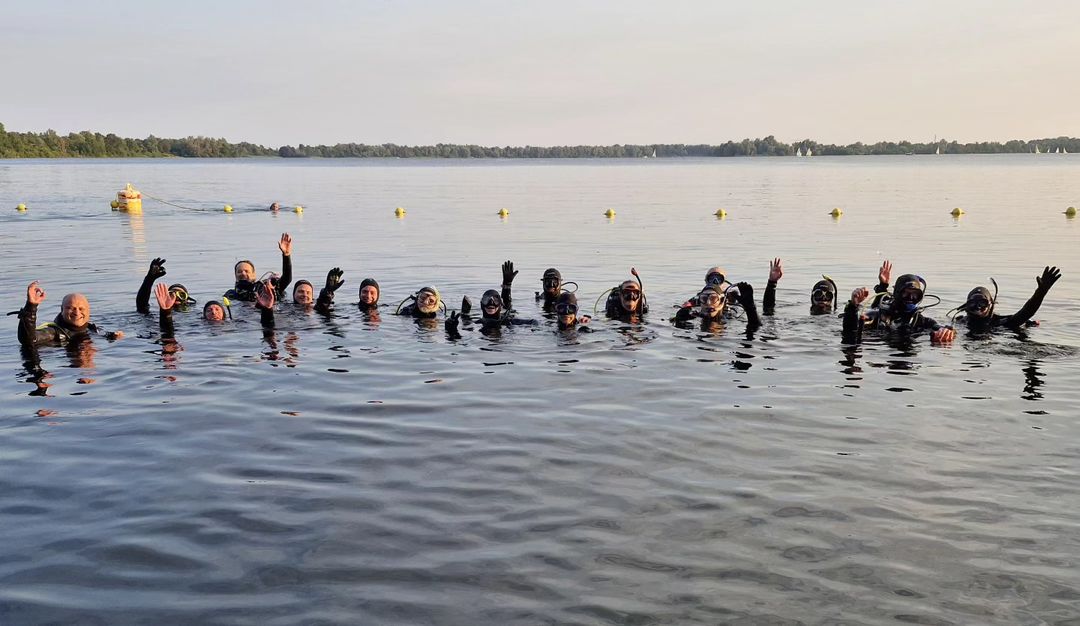 Groep duikers zwaait vrolijk vanuit het water