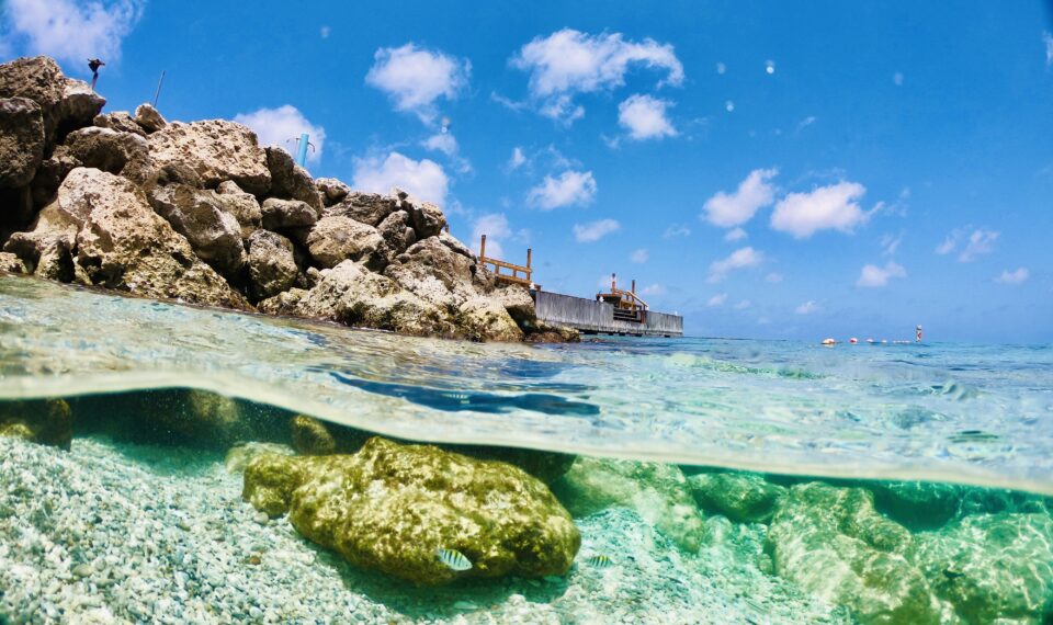 Splitshot van tropisch helder water met rotsen en een steiger